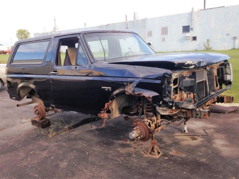 1992 Ford Bronco - This heavily damaged SUV is missing its wheels and has significant front-end collision damage.