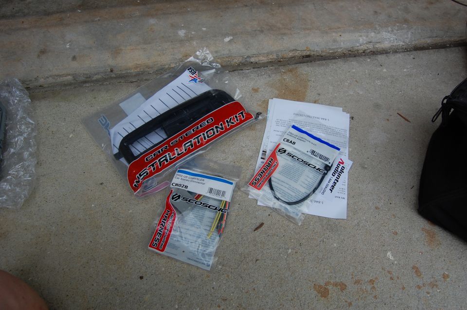 Car stereo installation kit and wiring harnesses on concrete.