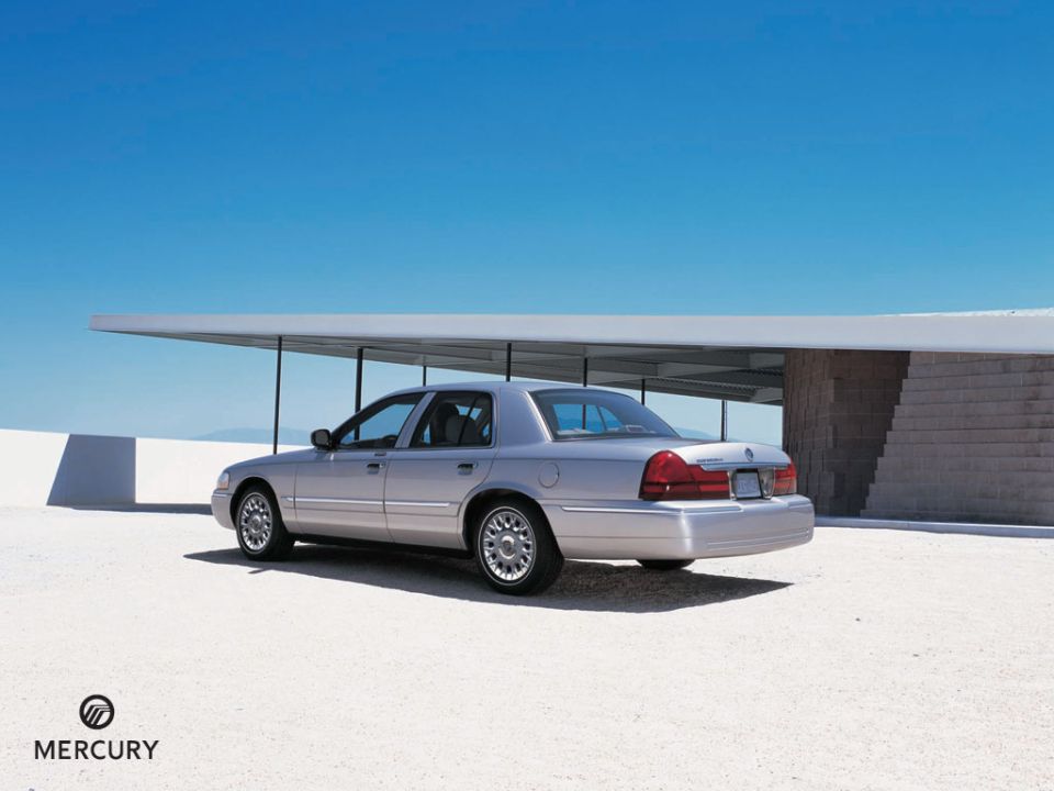 Silver sedan parked on a light-colored surface under a modern overhang, rear-left view