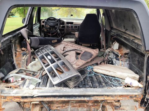 1992 Ford Bronco - The interior of the vehicle is in disarray, with parts and debris filling the cargo area.