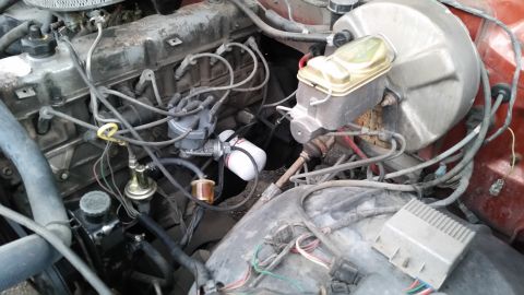 1981 Ford Bronco - A close-up view of a vintage vehicle's engine bay, showing various components like the brake master cylinder, distributor, and wiring harne…