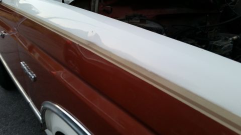 1981 Ford Bronco - A close-up, side view of the front fender and hood area of a classic two-tone vehicle. The lower portion is a deep reddish-brown, with a th…