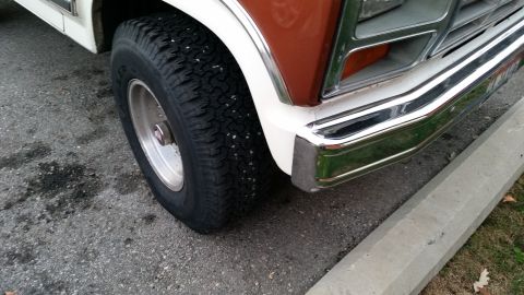 1981 Ford Bronco - Close-up shot of the front passenger-side tire and chrome bumper of a vintage Ford Bronco. The tire has small white specks on its tread, po…