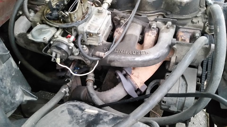 Close-up of an Edelbrock branded V8 engine intake manifold and carburetor with hoses and wiring.