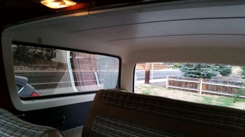 1981 Ford Bronco - Interior view of a vintage SUV, looking towards the rear passenger side window. The vehicle features plaid upholstery and a view of a woode…