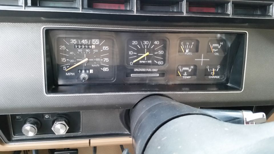 Vehicle dashboard instrument cluster with speedometer, tachometer, and other gauges.