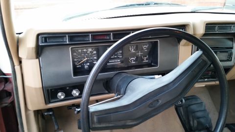 1981 Ford Bronco - The interior of a classic Ford Bronco is shown, focusing on the dashboard and steering wheel. The dashboard features a speedometer, fuel ga…