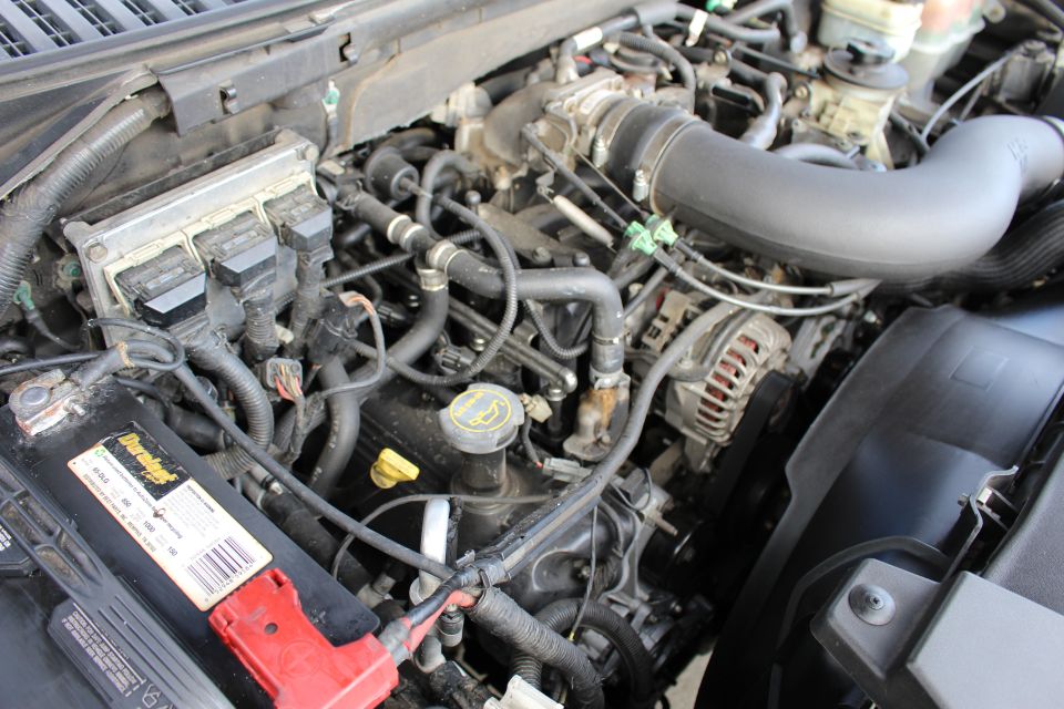 Close-up of a Ford Expedition engine bay with battery, ECM, and alternator visible.