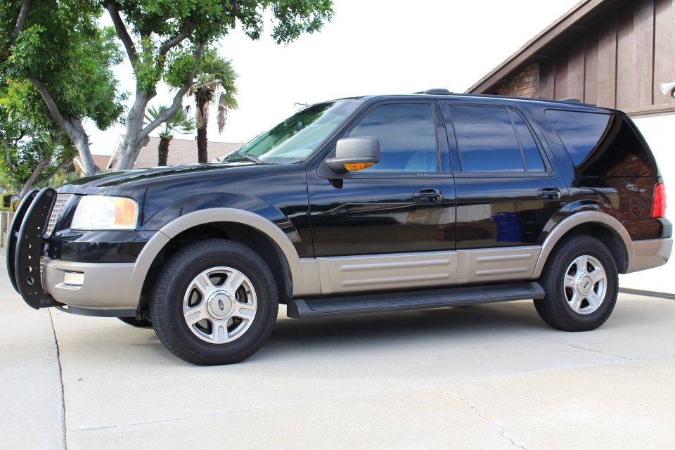 2003 Ford Expedition SUV, black with tan trim, side view, parked on concrete driveway.