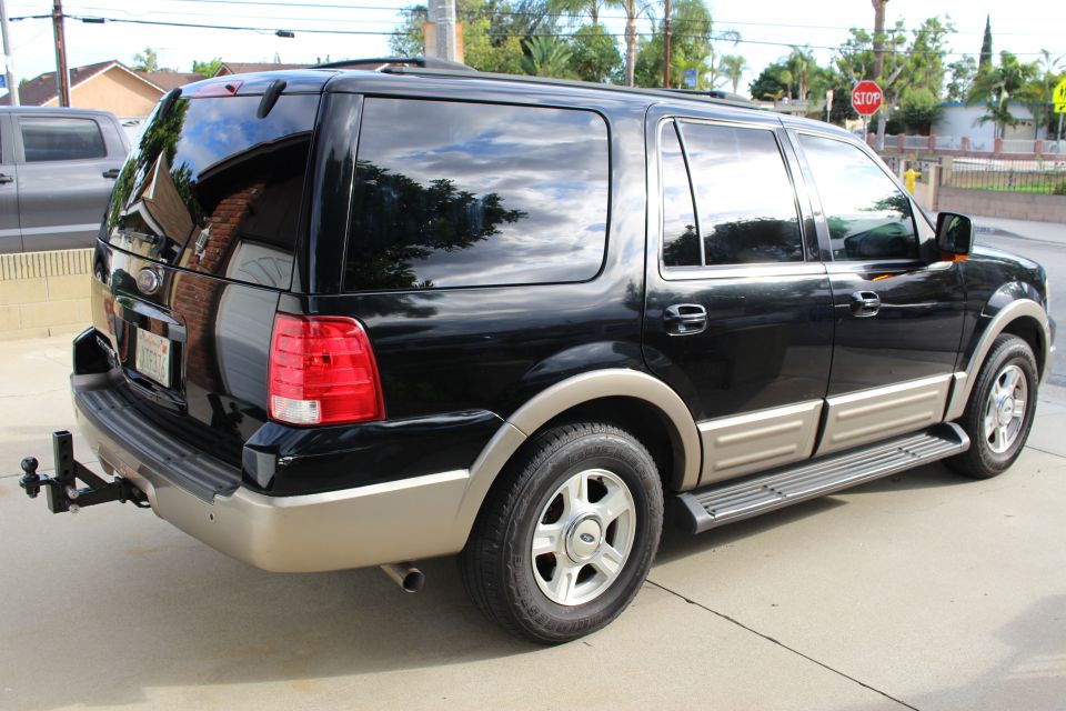 Black 2003 Ford Expedition SUV, rear passenger side view, with tan trim and trailer hitch.