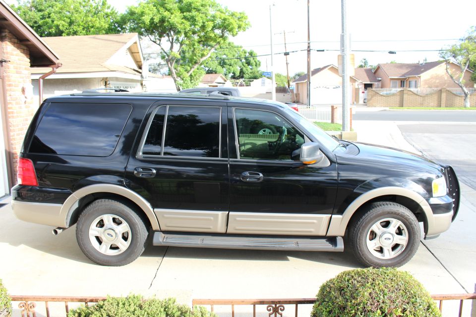 Black 2003 Ford Expedition SUV parked on a driveway, side view.