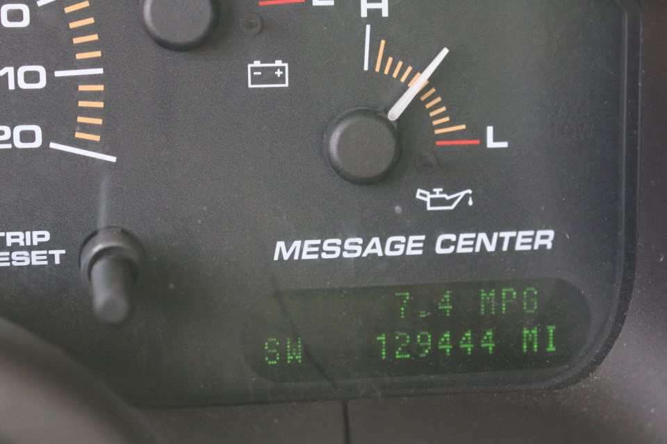 Vehicle dashboard with gauges and digital display showing MPG and mileage.