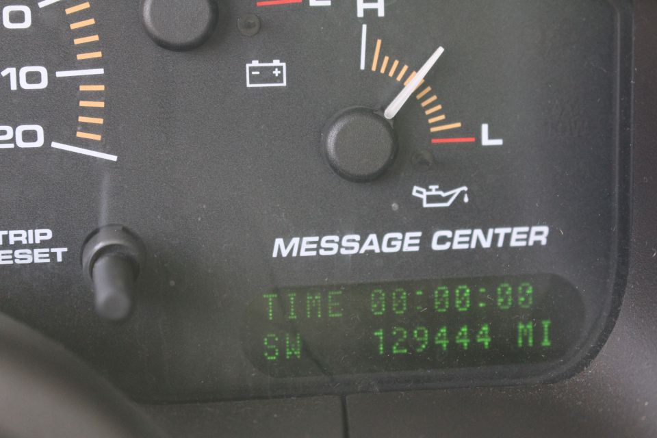 Close-up of a car dashboard with gauges and digital display showing time and mileage.