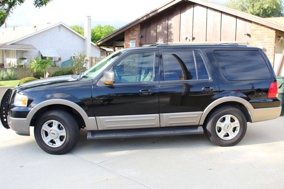 2003 Ford Expedition SUV, black with tan trim, parked on a driveway.