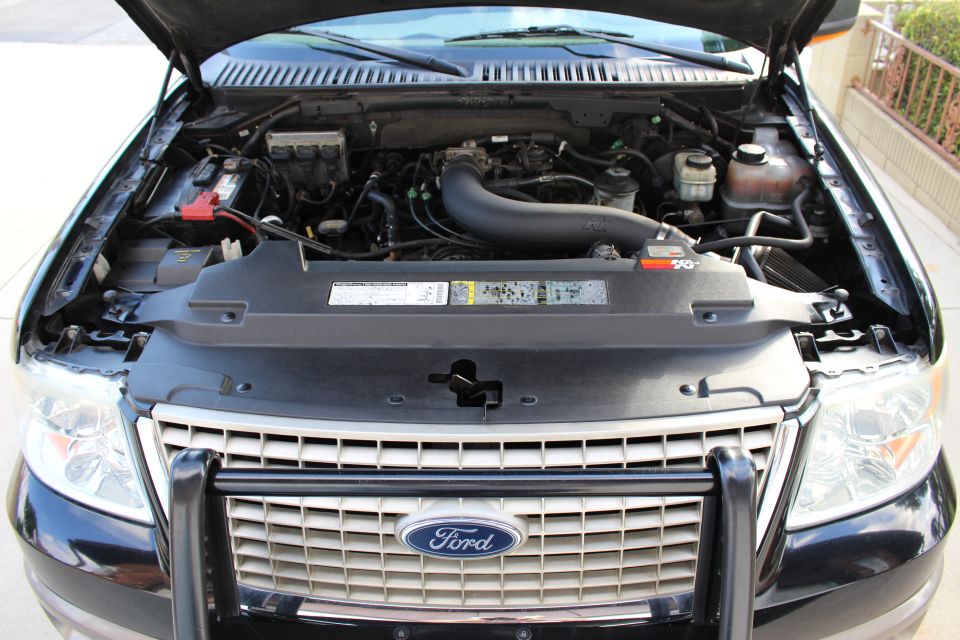 Front view of a 2003 Ford Expedition engine bay with the hood open. Shows the engine, battery, and grille
