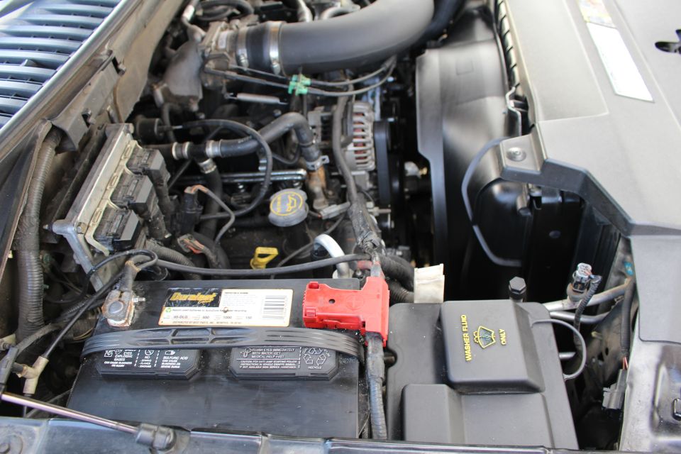 Engine bay showing battery, hoses, and fan. Washer fluid reservoir visible