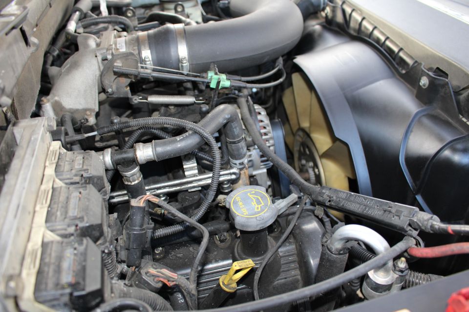 Engine bay with hoses, wiring, fan, and engine components visible