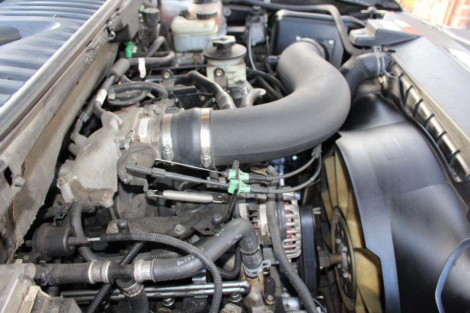 Close-up of a vehicle's engine bay, showing hoses, belts, and the fan