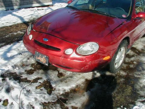 1997 Ford Taurus - Front view of a red 1997 Ford Taurus parked in the snow.