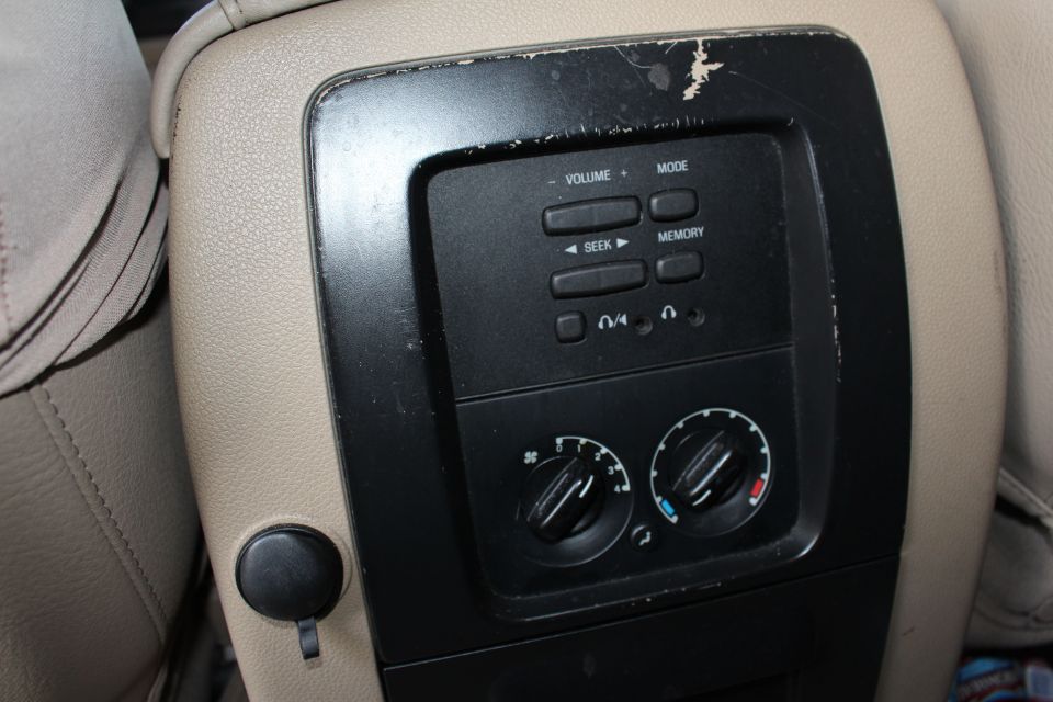 Center console of a 2003 Ford Expedition with worn climate controls and audio buttons