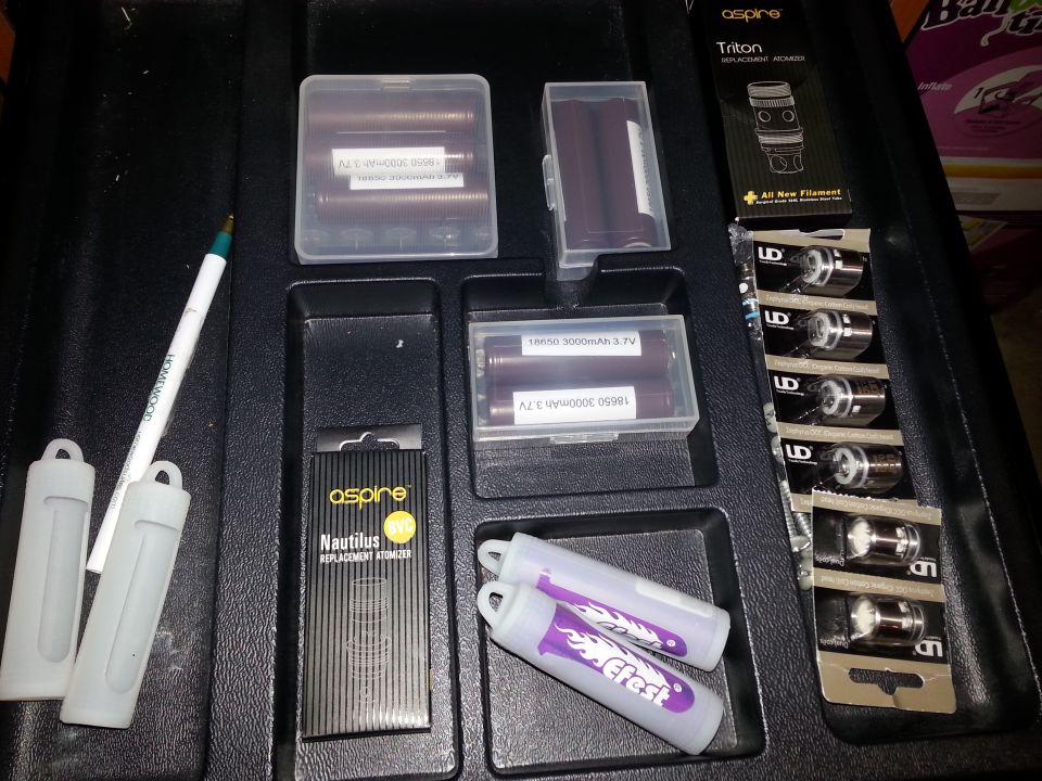 Vape batteries, coils, and a pen are laid out in a black organizer case