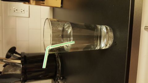1995 Ford Bronco - A glass of water with a straw is shown on a dark surface.