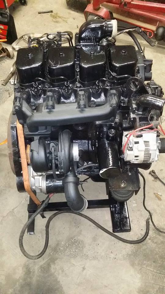 Black engine with turbocharger and alternator mounted on a stand