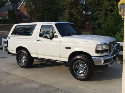 1995 Ford Bronco - A white Ford Bronco is shown from the front three-quarter view, parked on a concrete driveway.
