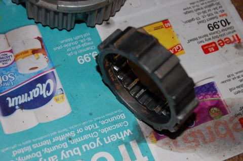 1994 Ford Bronco - Close-up of a metal gear part resting on a surface covered with newspaper advertisements.