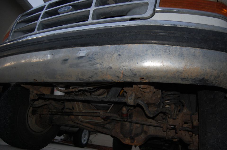 Ford truck grille and chrome bumper with scratches, viewed from below