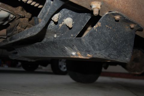 1994 Ford Bronco - Close-up view of a vehicle's underbody skid plate and suspension components.