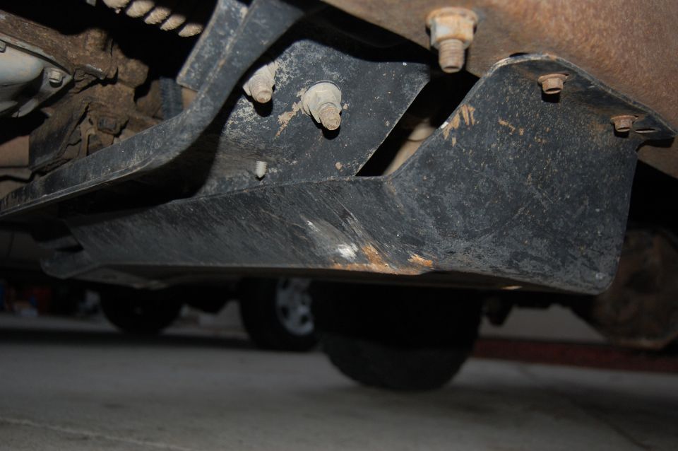 Underbody skid plate and suspension parts with visible rust and bolts