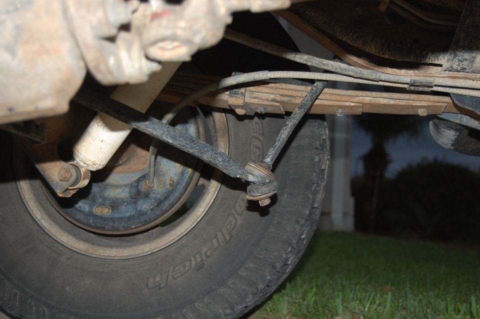 Underside view of a vehicle's rear tire, leaf springs, and shock absorber