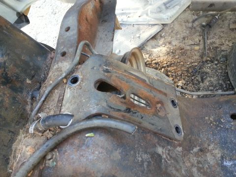 1994 Ford Bronco - Close-up of a corroded vehicle frame component with attached hoses and a pulley.