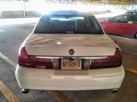 2000 Mercury Grand Marquis - The rear of a white Mercury Grand Marquis is shown, with a red car visible in the background.
