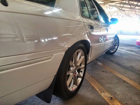2000 Mercury Grand Marquis - A white sedan is parked in a lot, showing its rear wheel and side panel.