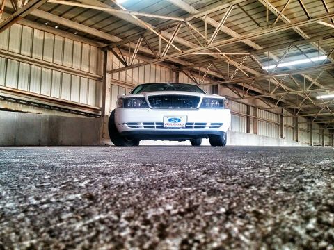 2000 Mercury Grand Marquis - Front view of a white 2000 Mercury Grand Marquis inside a large garage structure.