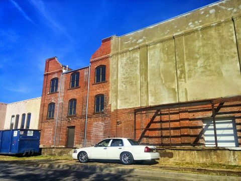 2000 Mercury Grand Marquis - A white sedan is parked on the street in front of old brick buildings under a bright blue sky.