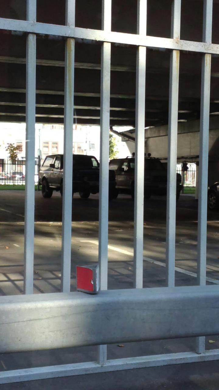 Dark 1987 Ford Bronco with camper shell, 3q front view behind metal bars