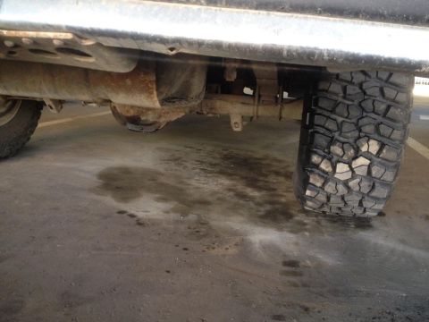 1987 Ford Bronco - Undercarriage view showing the rear axle, suspension, and a large off-road tire.