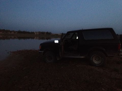 1987 Ford Bronco - A 1987 Ford Bronco sits by the water as daylight fades.