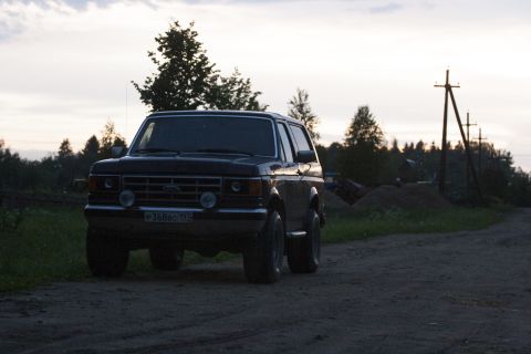 1987 Ford Bronco - A 1987 Ford Bronco is seen from a three-quarter front view on a dirt road, with a cloudy sky overhead.
