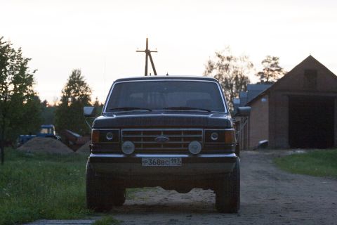 1987 Ford Bronco - Front view of a 1987 Ford Bronco parked on a dirt road near a barn.