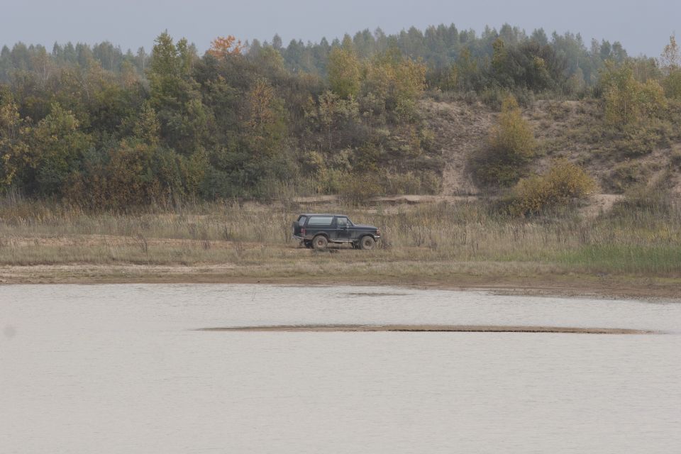 1987 Ford Bronco parked on a grassy bank near a body of water
