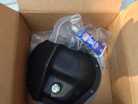 1979 Ford Bronco - A black differential cover and a tube of blue sealant are shown inside a cardboard box.