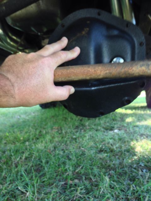 1979 Ford Bronco - Close-up view of a vehicle's differential housing with a hand obscuring part of the view.