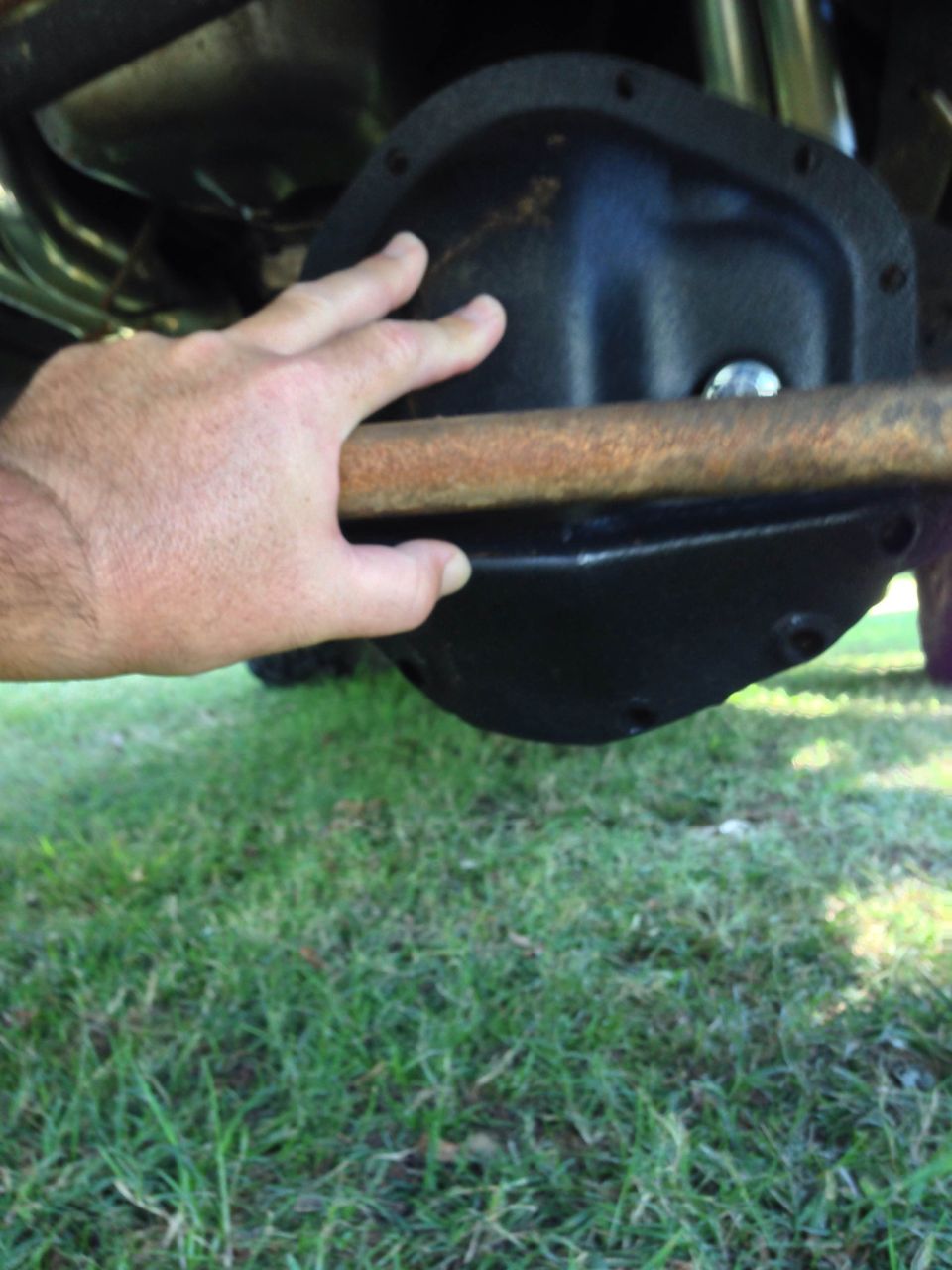 Differential housing with a hand resting on a rusty bar above it