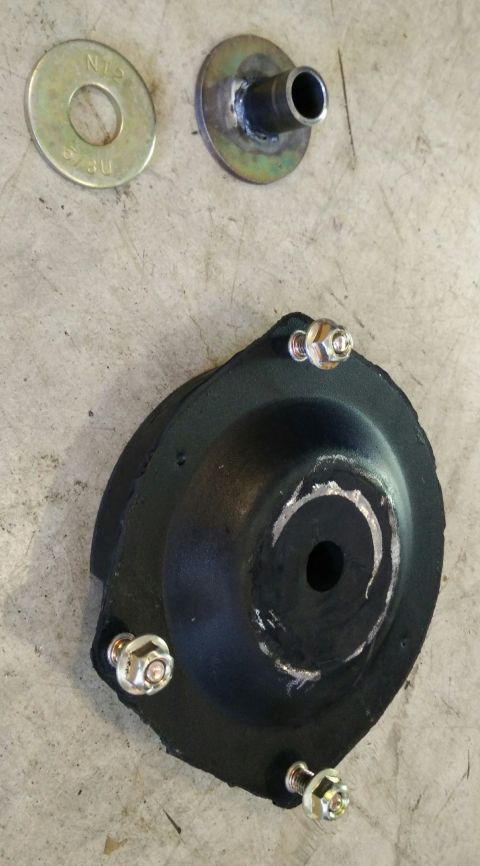 1993 Ford Thunderbird - A strut mount, washer, and bolt are shown on a concrete surface. The part appears to be for a vehicle.