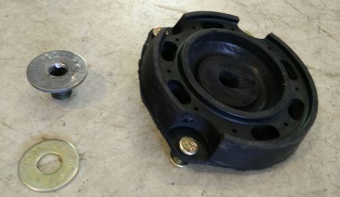 1993 Ford Thunderbird - A black rubber strut mount and associated hardware are shown on a concrete surface.