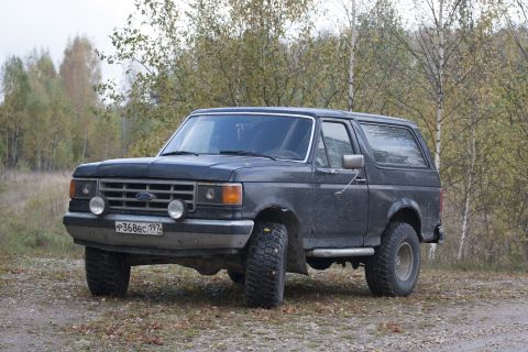 1987 Ford Bronco - This 1987 Ford Bronco is seen in a wooded area with a license plate visible on the front.